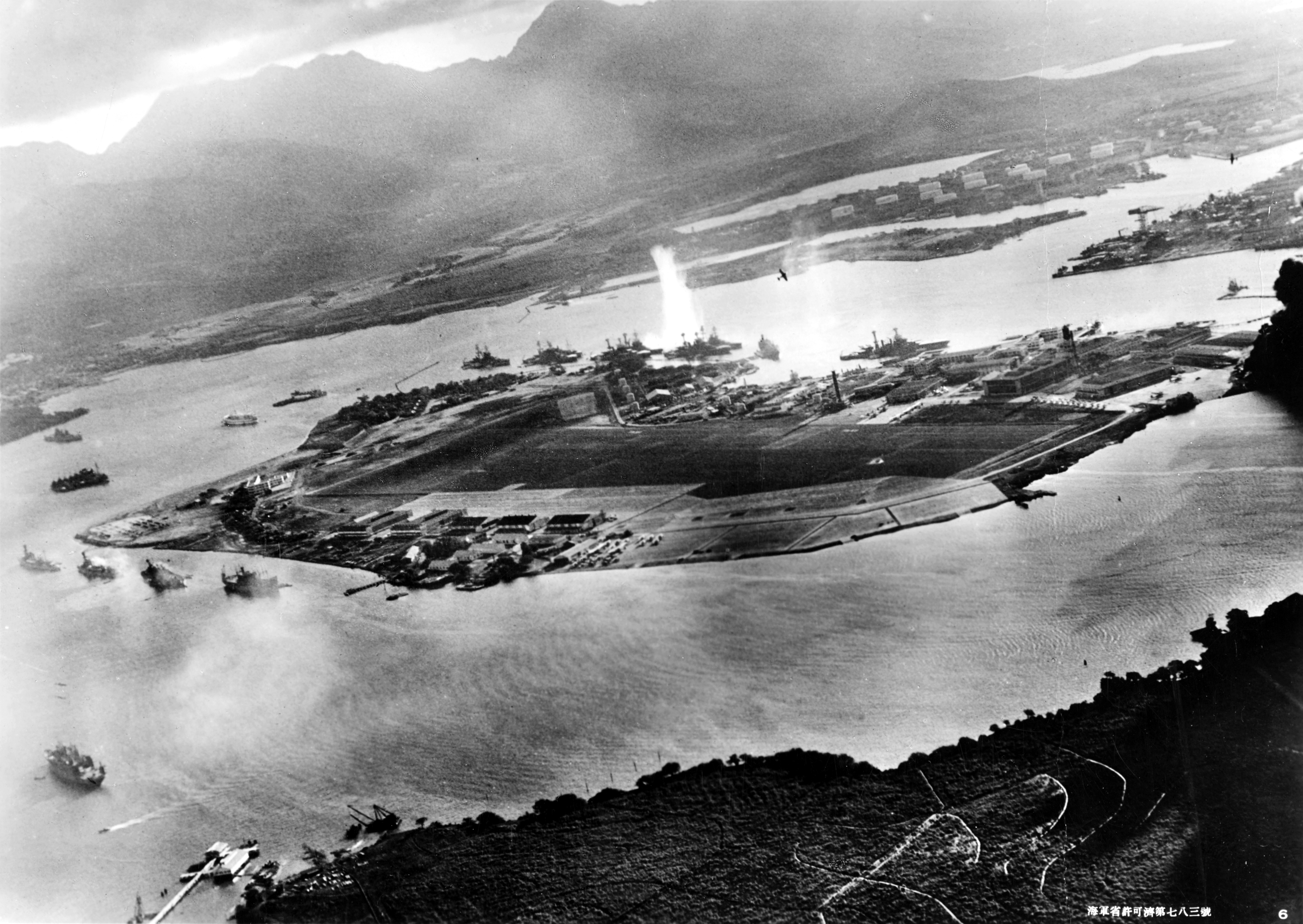 Photograph taken from a Japanese plane during the torpedo attack on ships moored on both sides of Ford Island shortly after the beginning of the Pearl Harbor attack. A torpedo has just hit USS West Virginia on the far side of Ford Island (center).